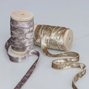 Detailed close-up of velvet ribbons in purple and champagne on vintage wooden spools