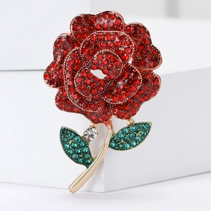 Exquisite gold-tone rose brooch with sparkling red and green rhinestones on a white background