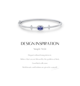 Macro detail of silver bangle featuring an oval blue gemstone and cubic zirconia accents
