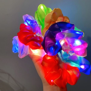 Detail showing various colors of LED hair scrunchies with vibrant glowing effect in hand