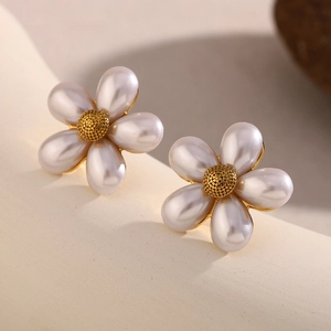 Close-up of pearl flower earrings with gold metal centers on a neutral beige backdrop
