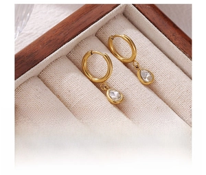 Detail of gold water drop zircon earrings on a beige velvet jewelry box tray