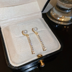 Macro shot of pearl earrings with micro-set zircon drop on beige velvet jewelry tray
