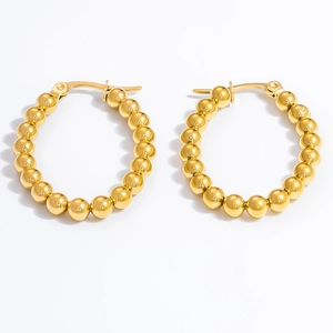 Detailed view of polished 18k gold plated beaded hoop earrings for women on white background