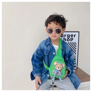 Toddler boy wearing a bright green crossbody chest bag with a cute cartoon bear print