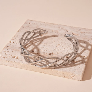 Detail of silver twisted mesh open bangle on textured stone with warm lighting