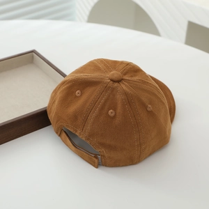 Detail view of the caramel brown baseball cap showing adjustable strap and corduroy texture