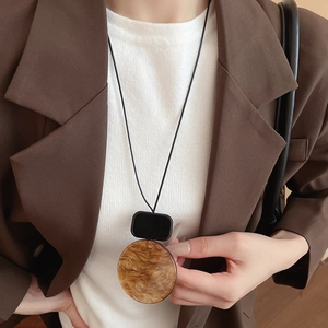 Detail of a geometric resin pendant necklace with brown marble texture on a long black cord