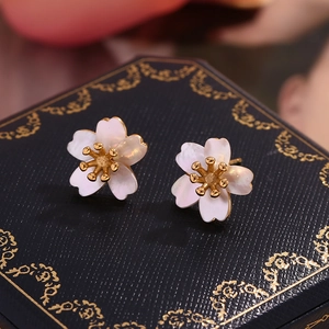 Macro shot of 18K gold plated cherry blossom stud earrings with white mother of pearl petals