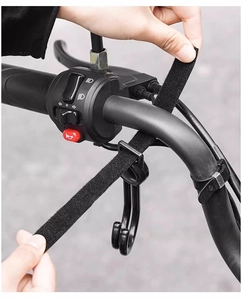 Manual installation of universal velcro hook on a black metal bike handlebar