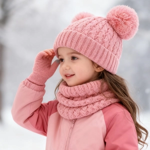 Close-up of pink knit kids' winter set with double pom-pom hat, scarf, and gloves