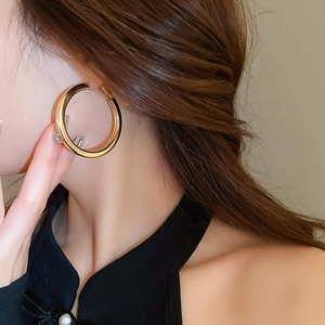 Close-up of a chunky golden hoop earring with a polished finish worn by a model