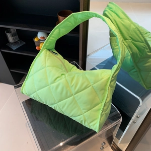 Detail view of neon green quilted nylon shoulder bag with zipper and puffy texture
