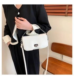 White minimalist crossbody bag with silver chain strap shown on a black suit jacket