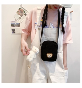 Detail of black corduroy mini crossbody bag with bear embroidery and plush charm