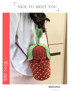 Detail of strawberry shaped woven crossbody bag with red body and green leaf top