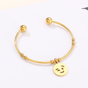 Detail of gold titanium steel open bangle with a polished winking emoji charm and beads