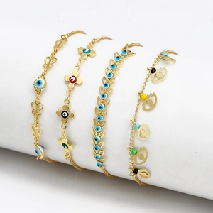 Dettaglio di quattro braccialetti dorati Evil Eye con ciondoli a farfalla e croce su basi