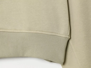 Vue macro détaillée de la texture du tricot vert olive et des poignets côtelés du sweat à capuche