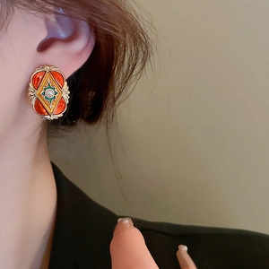 Detail of vintage enamel earrings with white pearl inlay on model showing retro style