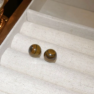 Close-up of vintage brown tiger eye stud earrings placed in a white jewelry gift box