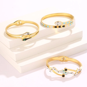 Detailed shot of gold-plated snake bracelets with sparkling stones and enamel eyes