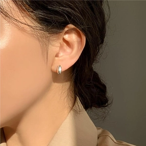 Detail of minimalist 925 sterling silver oval hoop earring on model under natural light