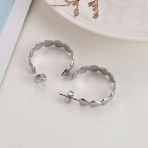 Detailed view of silver heart-shaped hoop earrings on elegant white textured surface