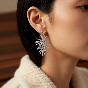 Close-up of starburst drop earrings with silver plating and cubic zirconia on model