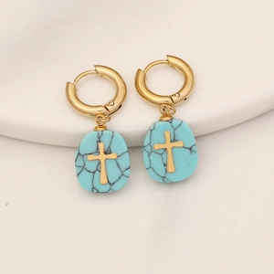Detail of cross charm earrings with turquoise stone pendants and polished gold finish