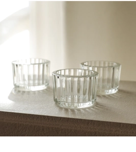 Detail view of ribbed crystal glass candle holders on a textured stone surface
