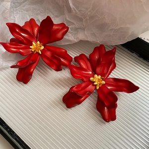 Detailed close-up of vibrant red acrylic flower earrings with crystal beaded centers