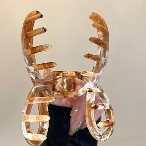 Detailed close-up of large amber marble acrylic hair claw with golden metal spring