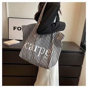 Detailed view of striped canvas tote bag with carpe diem text on female model