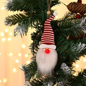 Hanging Christmas gnome ornament with red striped hat and warm bokeh light background