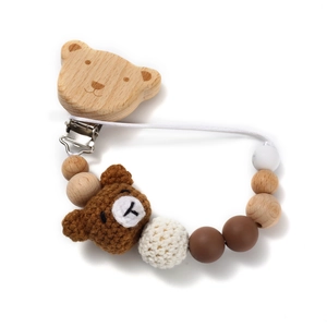 Detail of wooden bear clip and crochet bear doll on a baby pacifier chain accessory