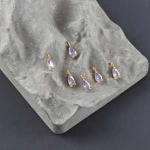 Detalle de colgantes de gota bañados en oro de 18k con piedras de circonita violeta