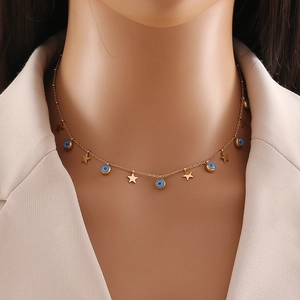 Detail view of gold layered necklace featuring blue evil eyes and star charms on model