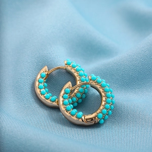Bohemian 18K gold earrings with turquoise beads and pearls on light blue fabric