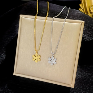 Gold and silver snowflake pendant necklaces in titanium steel on a professional display
