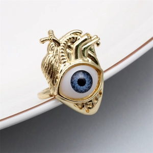 Detailed close-up of golden heart-shaped ring with a realistic blue eye inlay