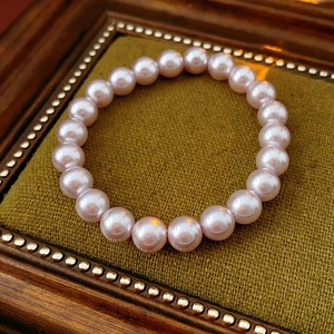 Close-up of elegant pink pearl beaded bracelet on a vintage dark green velvet display box