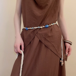 Detail of bohemian waist chain with blue and wooden beads on linen dress