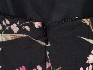 Close-up of floral linen dress showing hidden zipper and black beaded trim detail