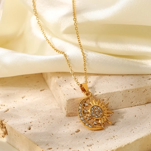 Close-up of gold-plated sun and moon pendant with white rhinestones on silk and stone