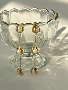 Detail of 18k gold vintage drop earrings with pearls on ripple glass background