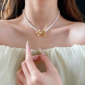 Detail view of pearl necklace with amber flower pendant on model neck