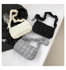 Detailed view of cloud-shaped pleated handbags in beige, black, and silver metallic colors