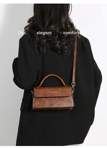 Borsa a tracolla vintage marrone caramello indossata da modella con cappotto nero