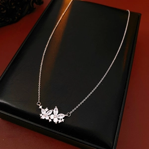 Gros plan d'un pendentif fleur en argent et zircon sur un écrin en cuir noir
